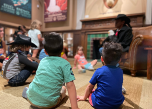 Children sitting and listening to a story at Storytime Stampede