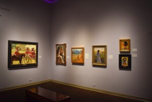 A picture of 6 painting being showed cased in the museum. All the pictures show different women in a western setting.