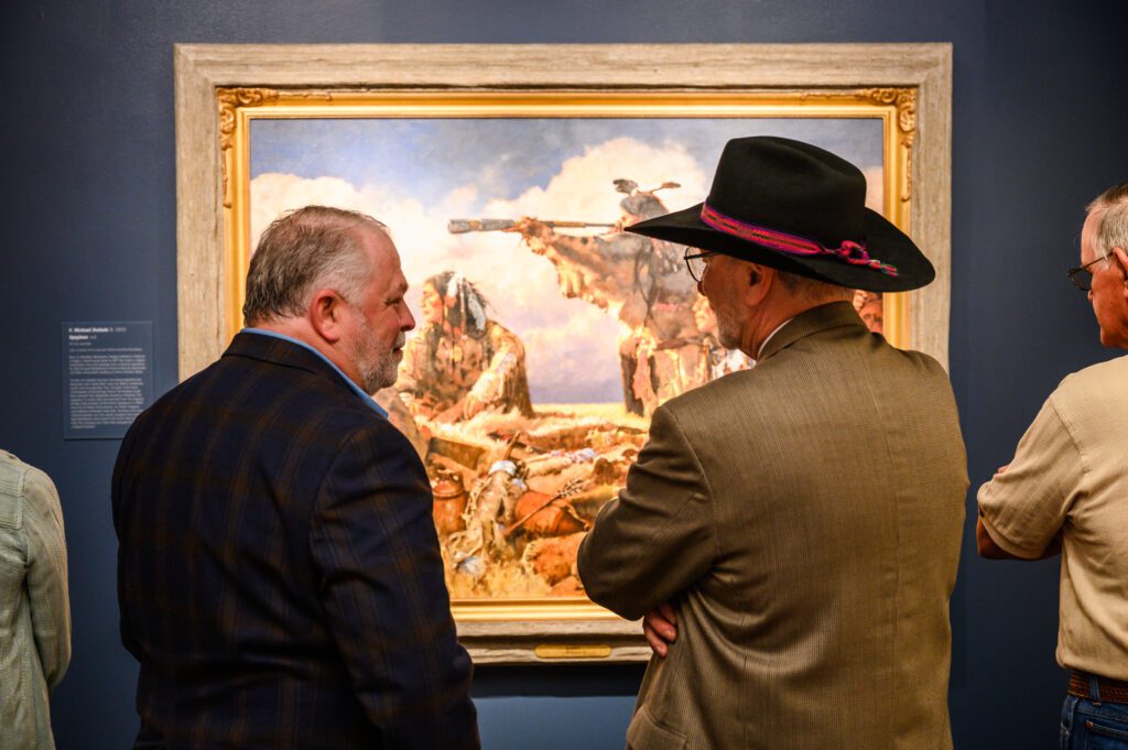 two men looking at a painting