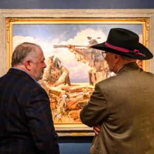 two men looking at a painting