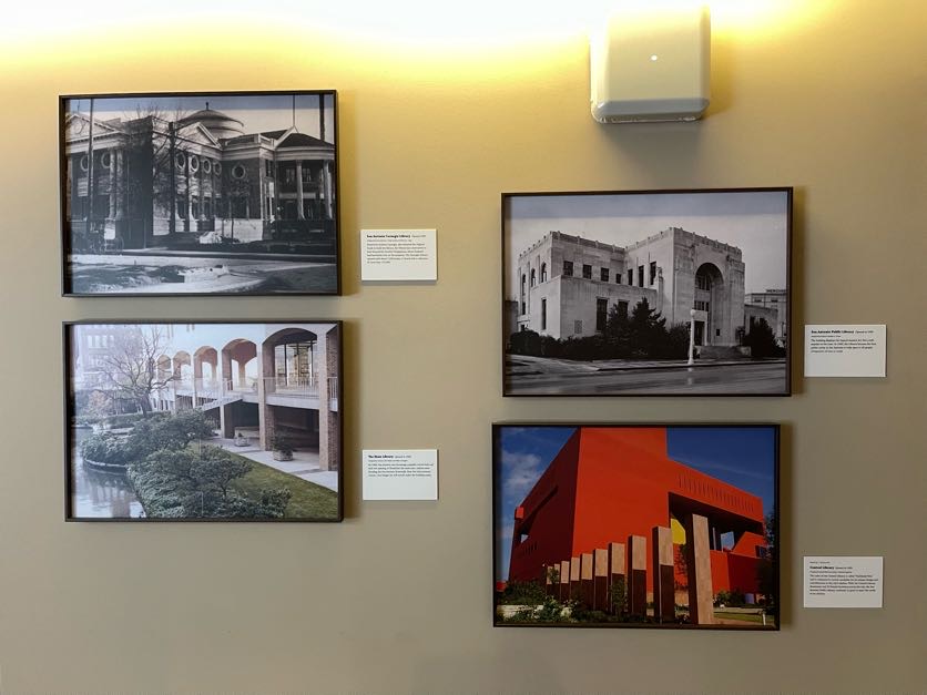 A wall with four paintings, showcasing buildings