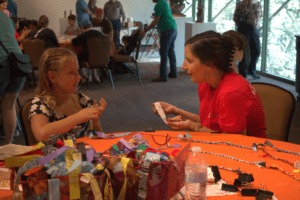 A child asking a question to a volunteer at a crafting table